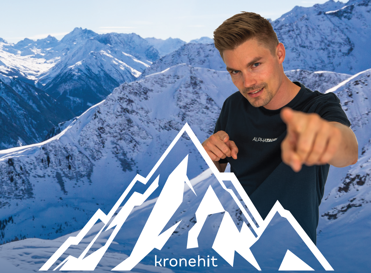 Ein Mann steht vor schneebedeckten Bergen und zeigt mit dem Finger nach vorne. Im Vordergrund ist das Logo von Kronehit zu sehen.