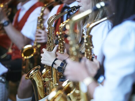 Eine Gruppe von Musikern spielt Saxophon. Sie tragen traditionelle Kleidung und konzentrieren sich auf ihre Instrumente.