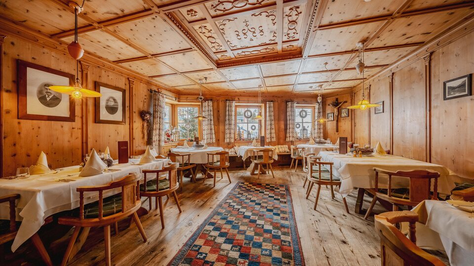 Ein gemütliches Restaurant mit Holzwänden und Tischen. Der Raum ist warm beleuchtet und hat ein einladendes Ambiente.