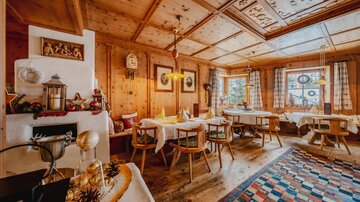 Ein gemütliches, holzvertäfeltes Restaurant mit mehreren Tischgedecken. Sanfte Beleuchtung und traditionelle Dekoration schaffen eine einladende Atmosphäre.