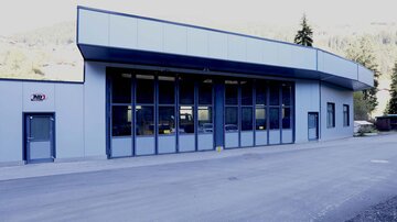 A modern building with large windows and a flat roof. It is located in a rural area.