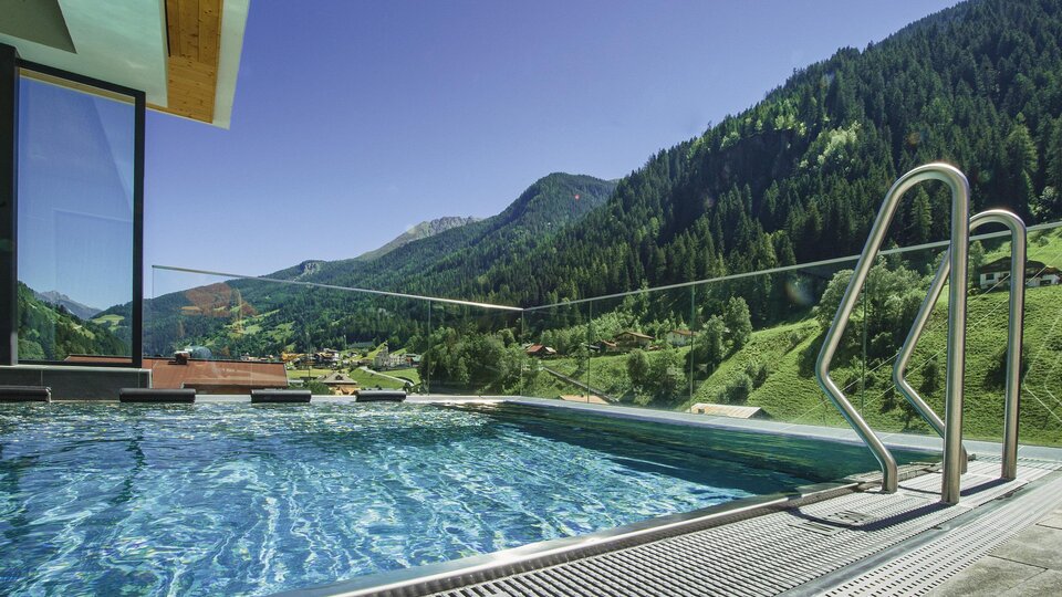 Ein moderner Infinity-Pool mit klar Wasser und Blick auf grüne Berge. Die Umgebung ist friedlich und einladend.