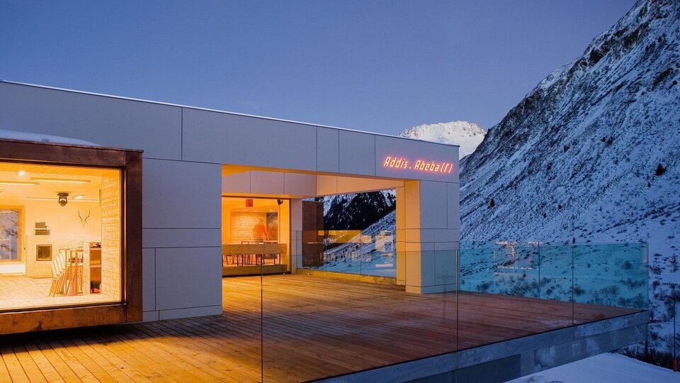 A modern house in the mountains, surrounded by snow. The balcony offers a magnificent view of the surrounding mountains.