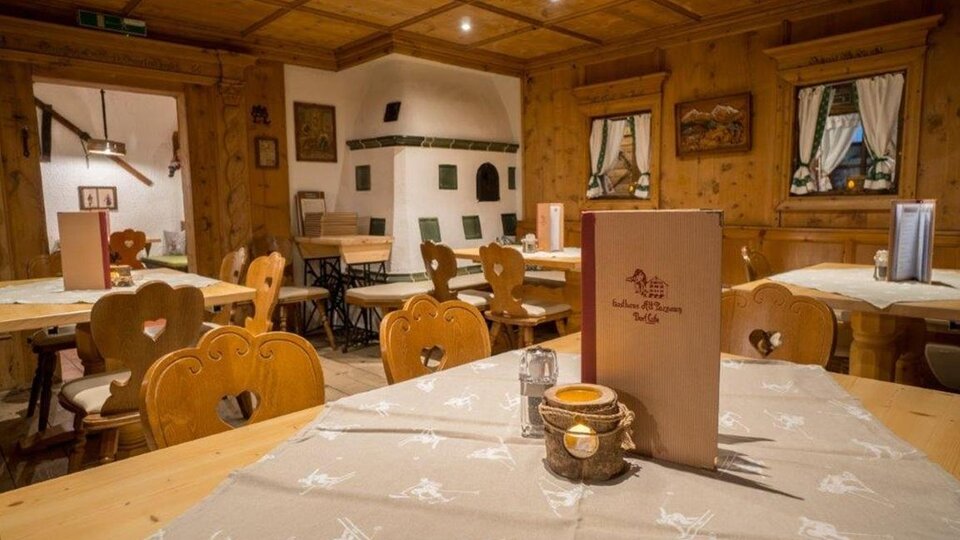 A cozy restaurant with wooden paneling and rustic tables. The tables are neatly set, and there is an inviting atmosphere.