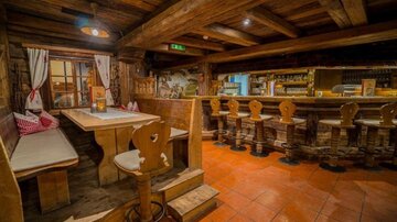 A cozy restaurant with rustic wood interior. The seating consists of benches and stools at a bar.