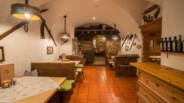 A cozy restaurant with wooden furniture and warm lighting. The walls are traditionally designed, creating an inviting atmosphere.