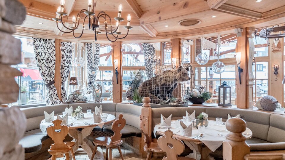 A cozy restaurant with wooden decor and a bear figure in the background. The tables are nicely set, creating an inviting atmosphere.