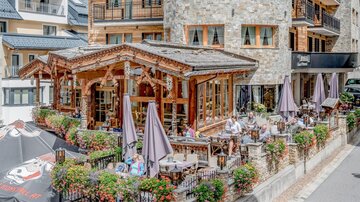 A cozy restaurant with a wooden veranda and terrace seating. Many guests enjoy the outdoor atmosphere.