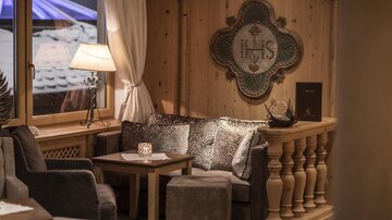 A cozy seating area with a comfortable sofa and chairs. Soft lighting and warm wooden paneling create an inviting atmosphere.