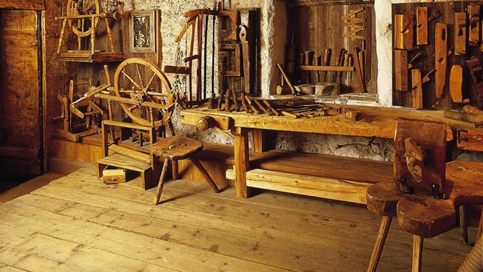 A traditional workshop with various woodworking tools. The wooden surfaces and furniture create a rustic atmosphere.
