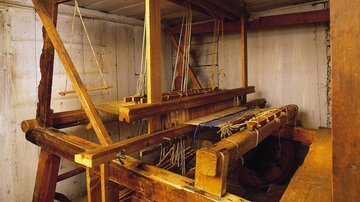 A traditional wooden loom in an interior. The structure displays various components for the weaving technique.