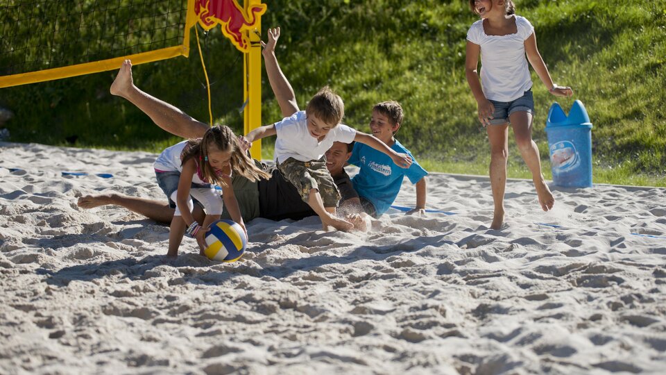 Kinder spielen Volleyball am Strand. Sie haben Spaß im Sand und genießen die Sonne.