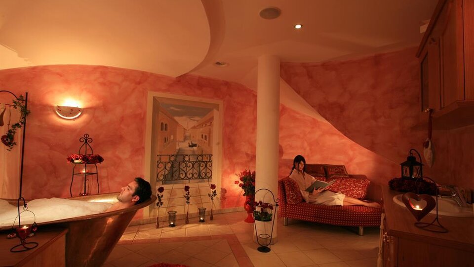Ein entspannendes Badezimmer mit einer Badewanne und einer gemütlichen Couch. Sanftes Licht und warme Farben schaffen eine beruhigende Atmosphäre.
