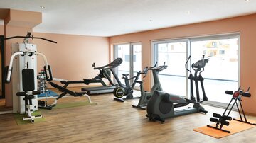 Ein modernes Fitnessstudio mit verschiedenen Trainingsgeräten. Der Raum ist hell und freundlich gestaltet.