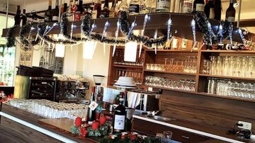 A modern bar with wooden shelves and an elegant counter. The bottles are neatly arranged and there are glass light accents.