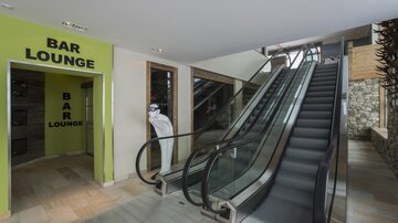 A modern entrance area with an escalator and a section for the bar lounge. The walls are painted in light colors, creating an inviting atmosphere.