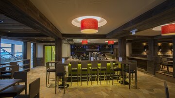 A modern restaurant with a stylish bar. Red lamps hang from the ceiling, creating an inviting atmosphere.