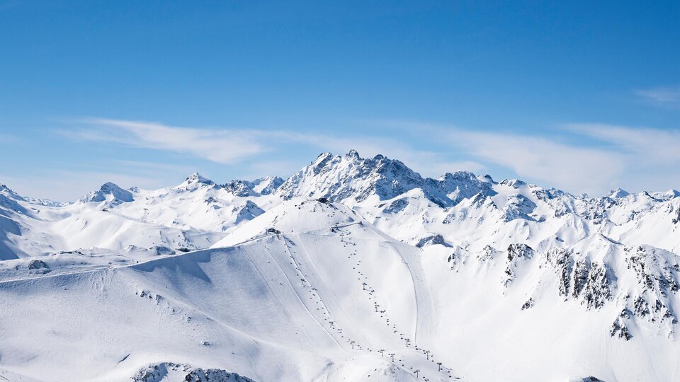 A picturesque winter landscape with snow-covered mountains and clear blue sky. Ideal for skiers and nature lovers.