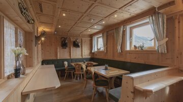 A cozy, wood-paneled restaurant with tables and chairs. Large windows provide plenty of daylight and an inviting atmosphere.