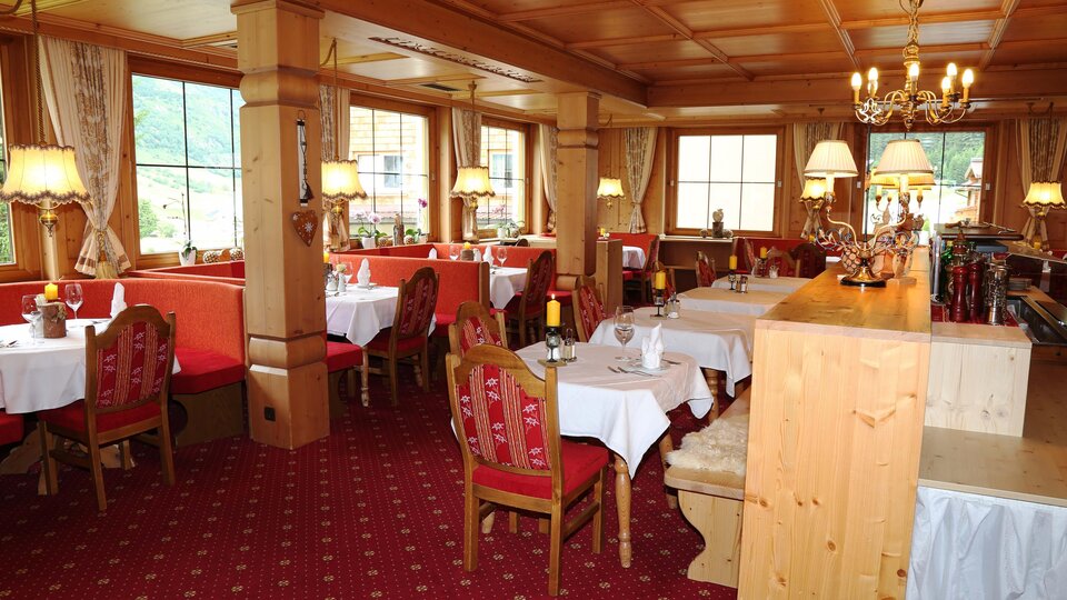 Ein gemütliches Restaurant mit Holzmöbeln und roten Sitzen. Sanfte Beleuchtung schafft eine einladende Atmosphäre.