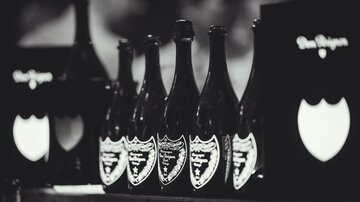 A series of elegant champagne bottles in black and white. In the background, stylish menus can be seen.