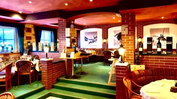 A cozy restaurant with a warm atmosphere. The room is equipped with red-stone walls and comfortable tables.