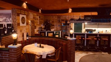 A cozy restaurant with wooden decor and an inviting bar. The atmosphere is warm and welcoming, perfect for a dinner.