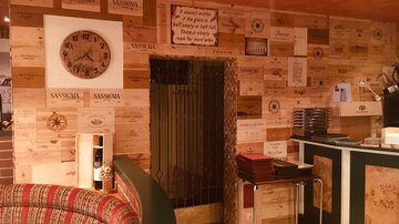 A cozy restaurant area with a wall of wooden panels and a large wall clock. The decor is rustic and inviting.