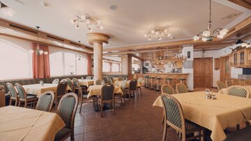 A cozy restaurant with tables in bright yellow and wooden chairs. The decor is rustic and inviting, with large windows that let in plenty of light.