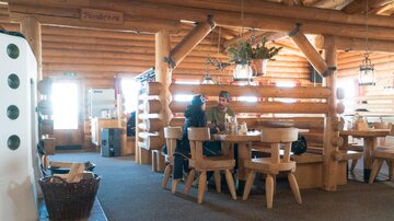 A cozy restaurant with wooden interior and rustic tables. Two people are sitting together at a table and enjoying their time.