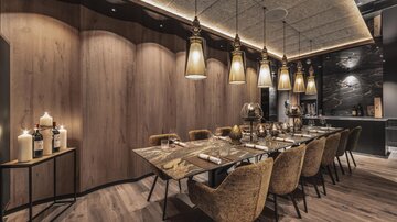 An elegant dining area with a long table and stylish chairs. The soft lighting creates a cozy atmosphere.