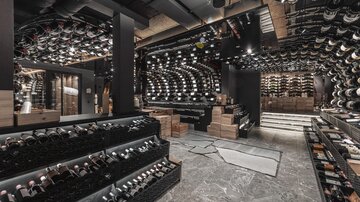 An elegant wine room with shelves full of wine bottles. The modern decor conveys a stylish atmosphere.