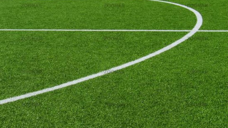 A close-up of a soccer field with green artificial turf. The white lines indicate the playing area.