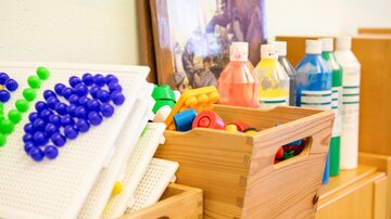 A play area with colorful toys and materials. There are boxes with building blocks and bottles in various colors.