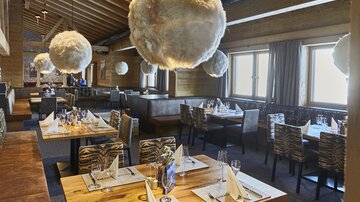 A stylish restaurant with wooden walls and elegant tables. The eye-catching, round lamps add a modern touch to the atmosphere.