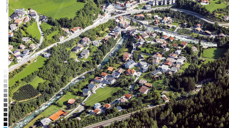 A picturesque view of a village with many houses and surrounding nature. Green meadows and forests surround the tranquil landscape.