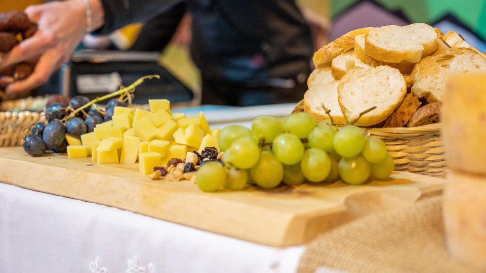 Ein schön gedeckter Tisch mit frischem Brot, Käse, Trauben und Nüssen. Die farbenfrohe Präsentation lädt zum Genießen ein.