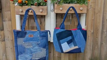Two stylish denim bags hang on a wooden wall. Above them, orange flowers bloom in flower boxes.