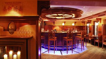 An elegant bar with wooden decor and stylish seating. Soft lighting and subtle colors create a cozy atmosphere.