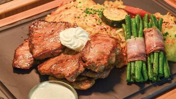 Ein köstliches Fleischgericht mit zartem Steak, einer Beilage aus Kartoffeln und Gemüse. Dazu gibt es frische grüne Bohnen und eine leckere Sauce.