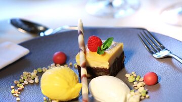 Ein kunstvoll angerichteter Dessertteller mit verschiedenen Eiskugeln, einer Mousse und bunten Dekorationen. Frische Beeren und Minze verleihen dem Gericht einen attraktiven Akzent.