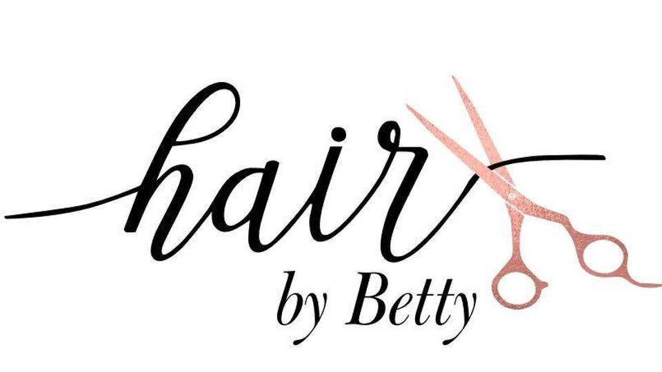 A stylish logo for a hair salon named "Hair by Betty". It features the lettering in an elegant font and a pair of scissors.