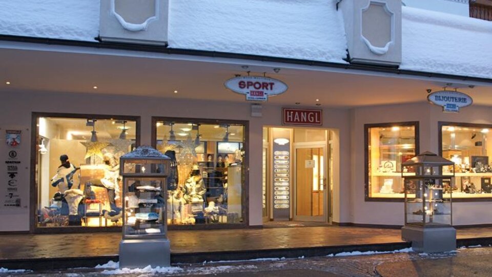 Ein Sportgeschäft mit einer schneebedeckten Fassade. Im Schaufenster sind verschiedene Sportartikel und Bekleidung zu sehen.