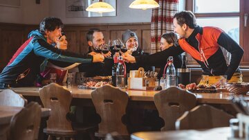 Eine Gruppe von Freunden sitzt an einem Tisch in einem gemütlichen Restaurant. Sie stoßen mit Gläsern an und feiern gemeinsam.