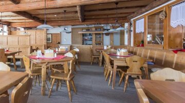 A cozy restaurant with wooden furniture and a warm atmosphere. There are several tables and an inviting decor.