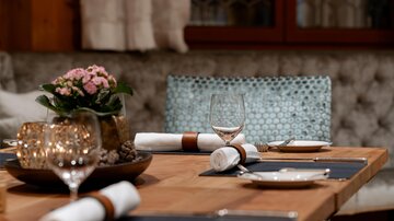 An elegant table with beautiful dishes and glasses, decorated with a small flowering plant. The atmosphere feels cozy and inviting.
