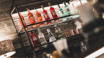 An elegant bartender with a shelf full of colorful spirits. The bottles are carefully arranged, creating an inviting atmosphere.