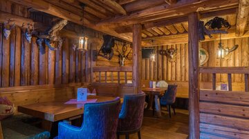 A rustic restaurant with wooden walls and cozy seating areas. The atmosphere is warm and inviting.