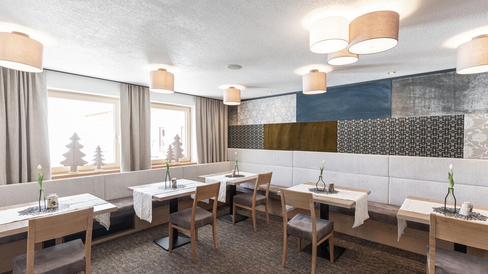 A modern restaurant with bright walls and stylish lamps. There are simple wooden tables and cozy chairs that create an inviting atmosphere.