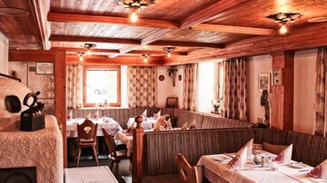 A cozy restaurant with wooden furniture and white tablecloths. The atmosphere is inviting with soft lighting and a rustic charm.